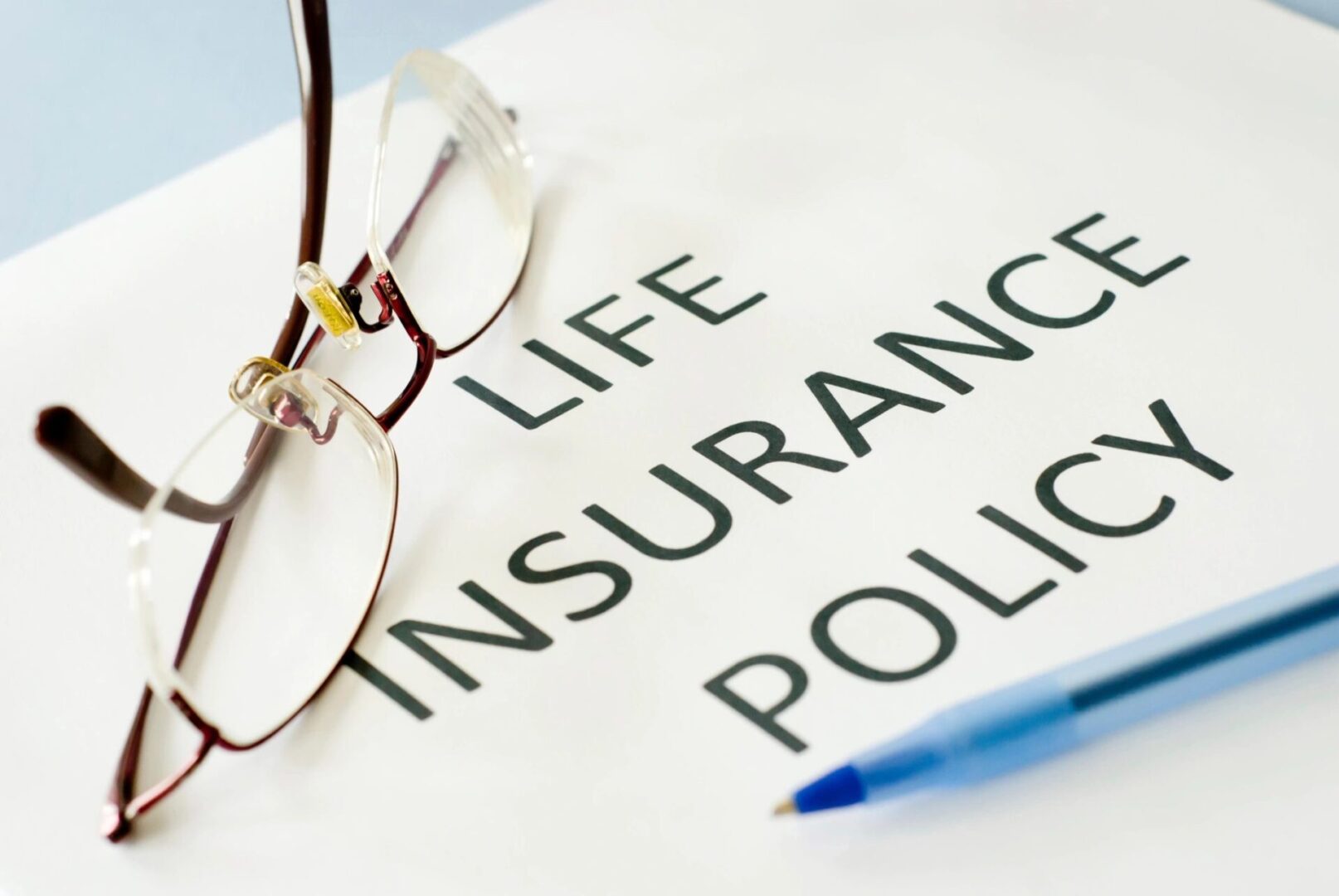 Life insurance policy with pen and glasses.