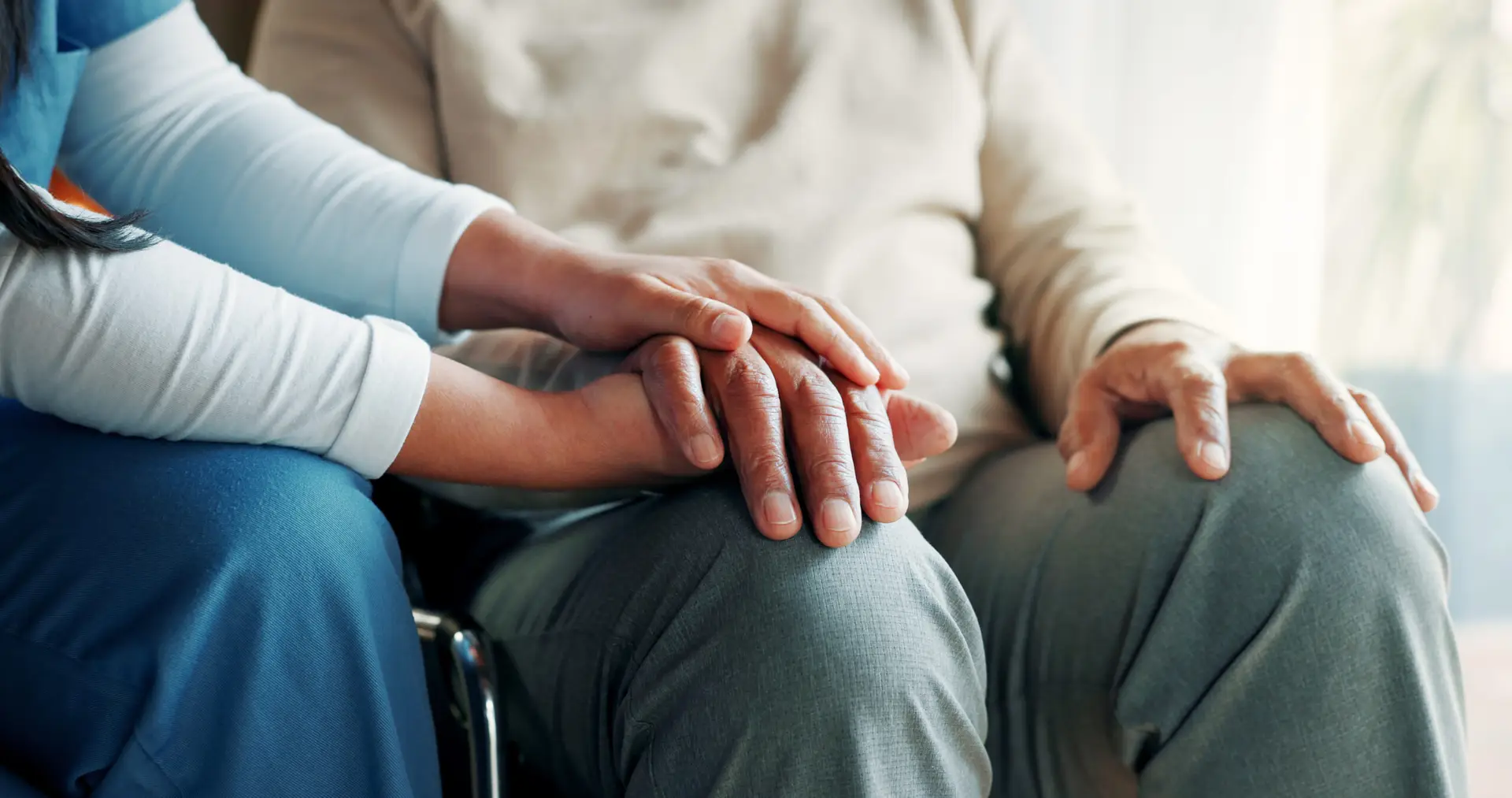 A caregiver gently holding hands with an older adult
