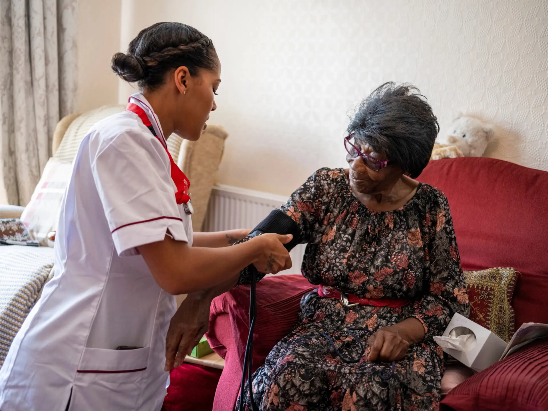 A nurse checking blood pressure during a home visit with an older woman